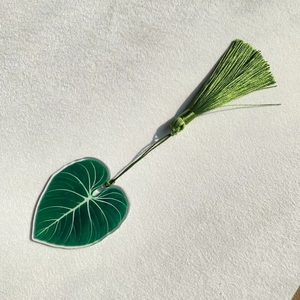 Detailed macro of green acrylic leaf bookmark with elegant silk tassel and realistic veins