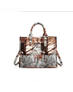 Front view of grey denim patchwork tote bag with reinforced handles and metal details