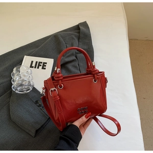 Detail der roten glänzenden Beuteltasche mit silbernem Logo und Knotengriff-Design