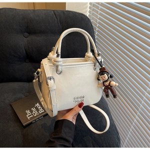 Detailansicht der weißen Bucket Bag aus Kunstleder mit Knotengriffen und Anhänger