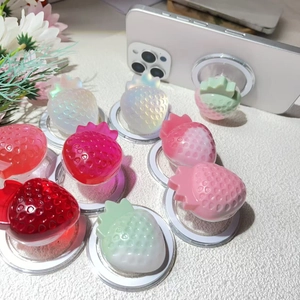 Detail of 3D resin strawberry MagSafe phone grip showing colorful 3D textures on a white phone