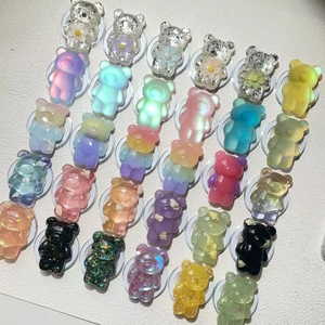 Collection of various bear-shaped phone socket grips in colorful glitter and gradient styles