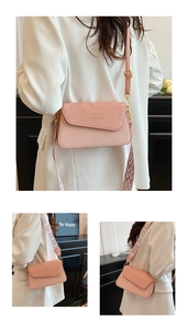 Pink crossbody bag with woven texture detail and patterned wide strap shown on model
