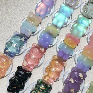 Detailed view of assorted resin bear phone grips with gradient and glitter finishes