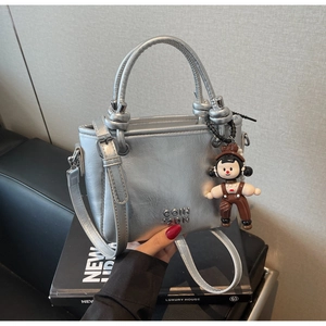 Silberne Metallic-Eimertasche mit süßem Anhänger und verstellbarem Schultergurt