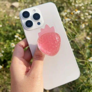Outdoor shot of a pink 3D resin strawberry griptok mounted on a white smartphone