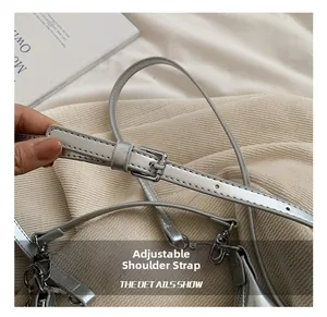 Détail d'une bandoulière argentée brillante réglable avec boucle et crochet en métal