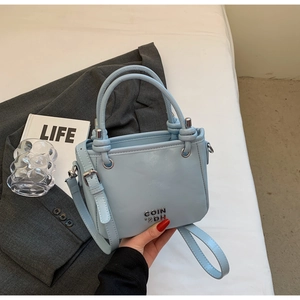 Detailansicht hellblaue Beuteltasche mit Metalllogo und verstellbarem Umhängeriemen