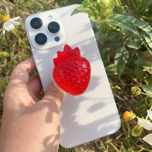 Macro detail of red resin strawberry phone grip showing textured surface and glossy finish