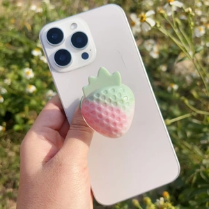 Detail of strawberry-shaped resin phone grip showing realistic texture and pink gradient