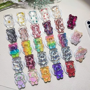 Detailed overhead view of 24 colorful bear-shaped resin phone grips with glitter and dried flowers