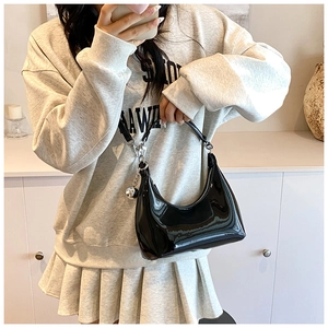 Sac hobo noir brillant avec chaîne argentée et pendentif sphérique porté par modèle