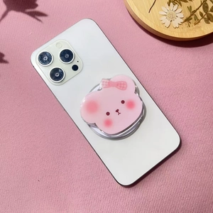 Close-up of cute pink acrylic bear phone grip on white phone over pink table