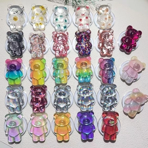 Macro shot of resin bear phone stands featuring dried flowers and glitter textures