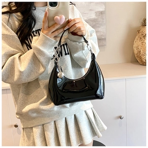 Détail du sac hobo en cuir verni noir avec breloque boule argentée et bandoulière minimaliste