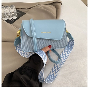 Detail of light blue crossbody bag with textured leather and geometric wide strap