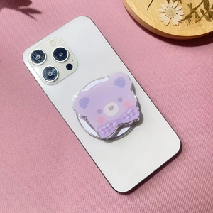 Detail of purple acrylic bear phone grip with plaid bow on a white smartphone back