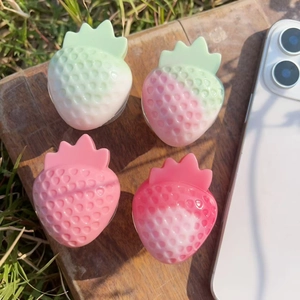 Detailed view of resin strawberry phone grips with gradient pink and green textures
