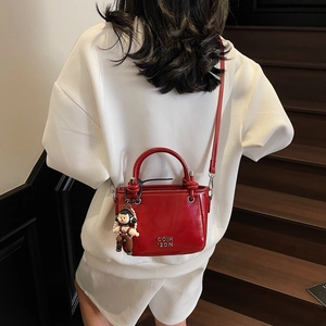 Rote Lackleder-Eimertasche mit Silberlogo und Anhänger an einem Modell