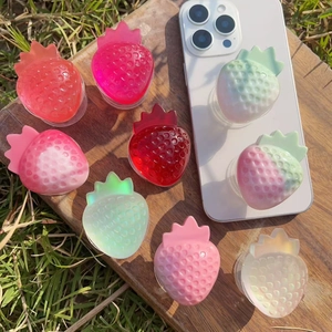 Detailed close-up of jelly texture strawberry-shaped phone grips on a wooden background