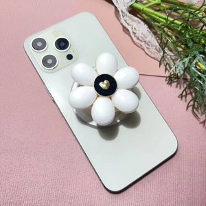 Detail of white flower phone socket with gold heart on pink textured background