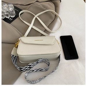 Detail of beige woven crossbody bag with dual straps and gold fashion lettering logo