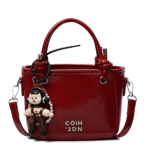 Glossy red bucket bag with cylinder handle and cute charm on white background