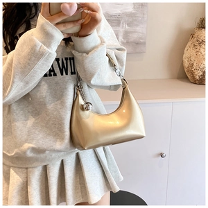 Détail du sac hobo doré métallisé avec chaîne à boules argentée et finition lisse brillante