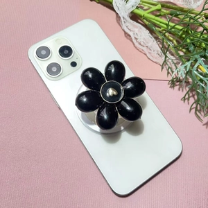 Detail of a black floral phone socket with a gold heart center on a white smartphone