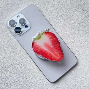 Detail shot of a magnetic strawberry phone grip with realistic fruit texture on iPhone