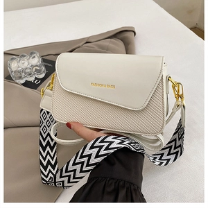 Detail of minimalist cream square bag featuring woven texture and gold fashion logo