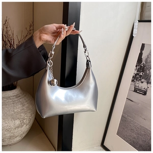 Détail du sac Hobo argenté brillant avec pendentif sphérique tenu par un mannequin