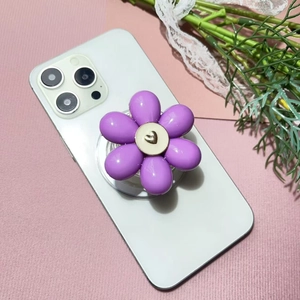 Macro detail of a purple floral phone grip with a gold heart center on a white smartphone