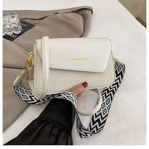 Detail of elegant cream shoulder bag with woven texture and geometric patterned strap