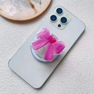 Detail of pink bow acrylic phone socket with heart accent on a white smartphone