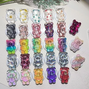 Variety of colorful resin bear pop sockets and Magsafe phone grips on a grey background