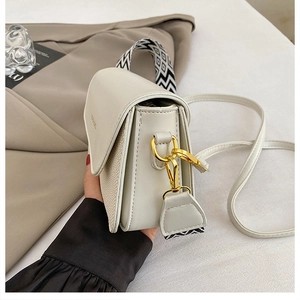 Detail of cream leather square bag with woven side and gold twist-lock closure