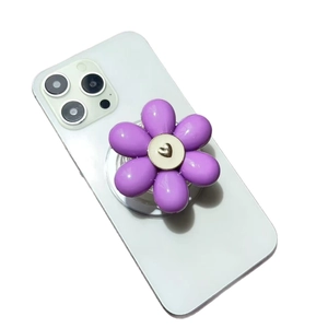 Collapsible purple flower phone grip stand with six petals on a white smartphone