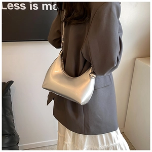 Détail d'un sac hobo argenté effet miroir avec breloque sphérique et texture métal