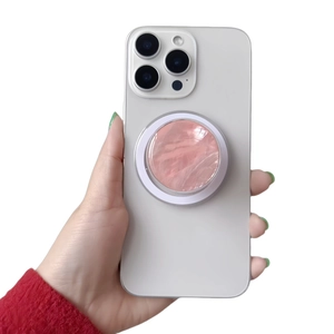 Detailed view of a magnetic phone grip with pink marble design on a white smartphone