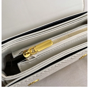 Detail of premium cream shoulder bag showing golden zipper and multi-layer inner pockets
