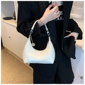 Gros plan sur le sac hobo en cuir verni blanc avec pendentif boule argentée et zip élégant