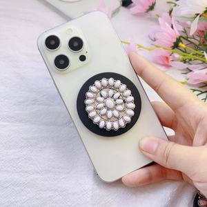 Detail view of a vintage flower phone grip with resin beads on a white smartphone