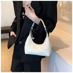 Gros plan du sac demi-lune en cuir verni blanc avec chaîne argentée et breloque sphérique