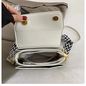 Detail of white leather shoulder bag with geometric strap and organized interior compartments