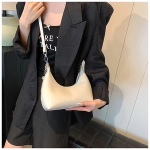 Détail du sac pois en cuir verni beige avec chaîne en métal et bandoulière réglable