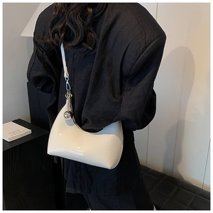 Détail d'un sac hobo en cuir verni beige brillant avec des breloques sphériques argentées