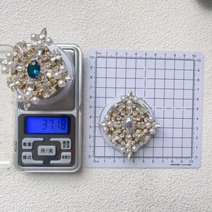 Detailed scale view of a luxury rhinestone snowflake brooch with pearls and blue center stone