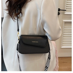 Detail of black leather crossbody bag with woven texture and gold fashion lettering