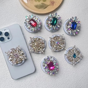 Detailed view of assorted luxury rhinestone and pearl phone socket stands on white surface